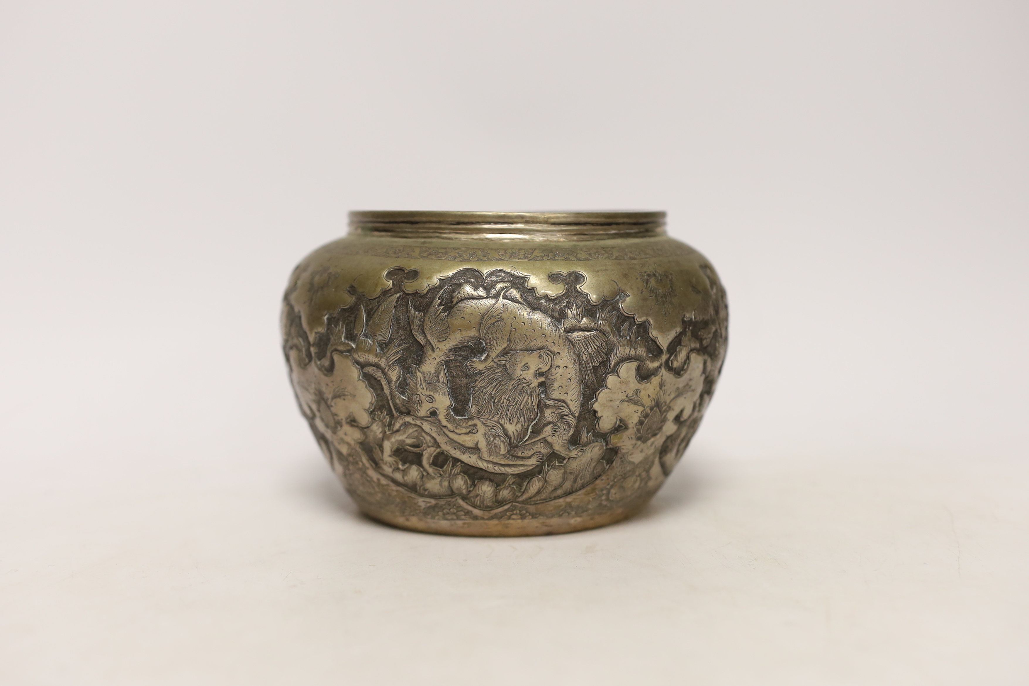 A Persian white metal bowl decorated in relief with animals and flowers, indistinct marks to the base, 16cm wide